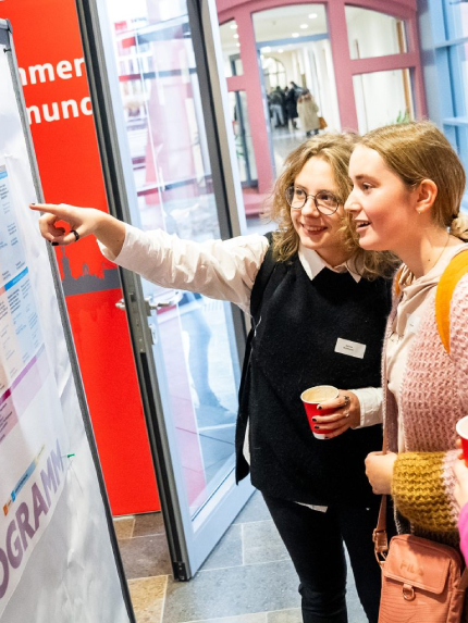Junge Frauen vor einer Plakatwand. Copyright für dieses Bild: Udo Geisler